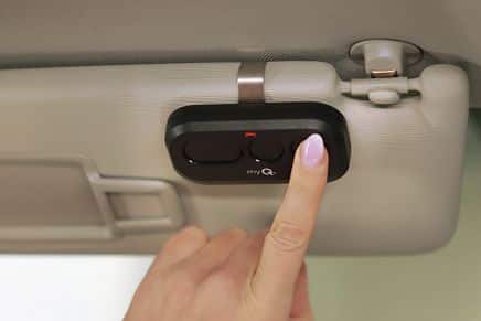 Hand pressing button on LiftMaster L993M remote clipped to car sun visor